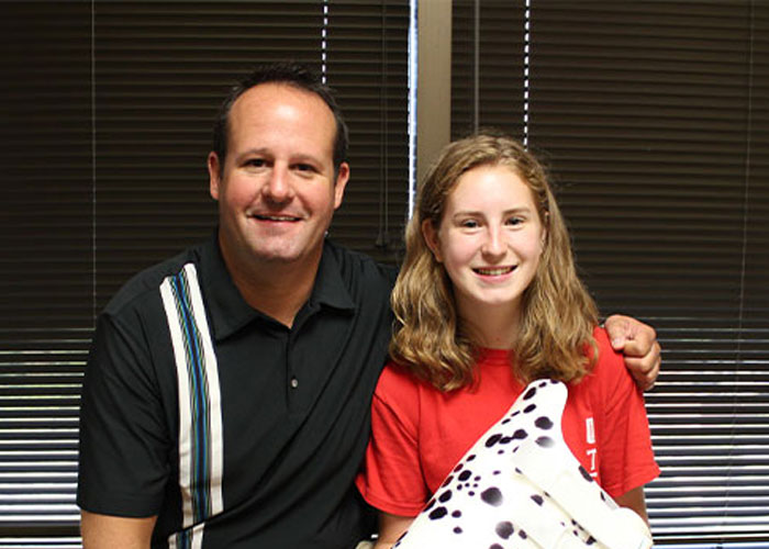 young girl sitting with Total Care employee and custom orthotic